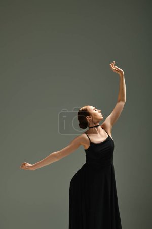 A young, beautiful ballerina dances gracefully in a black dress.