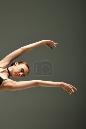 Foto de Talentosa bailarina joven con gracia realiza un truco impresionante en un maillot negro. - Imagen libre de derechos