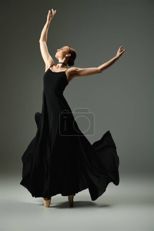 Téléchargez les photos : A young, talented ballerina gracefully dancing in a flowing black dress. - en image libre de droit