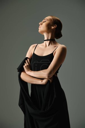 Eine junge schöne Ballerina in einem schwarzen Kleid mit verschränkten Armen.