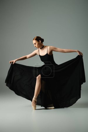 A young, beautiful ballerina in a black dress gracefully dances.