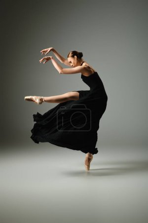 Téléchargez les photos : Une jeune, belle ballerine danse gracieusement dans une robe noire fluide. - en image libre de droit
