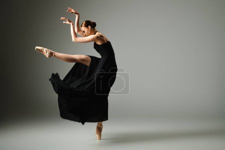 A young, beautiful ballerina in a black dress dances elegantly.