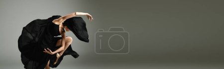 A young, beautiful ballerina dances gracefully in a sleek black dress.