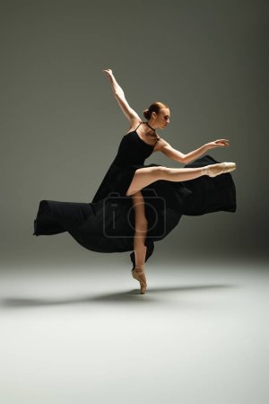 Young, beautiful ballerina dances gracefully in a black dress.