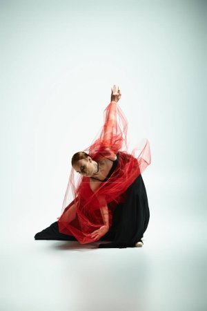 Anmutige Ballerina mit rotem Schleier tanzt auf dem Boden