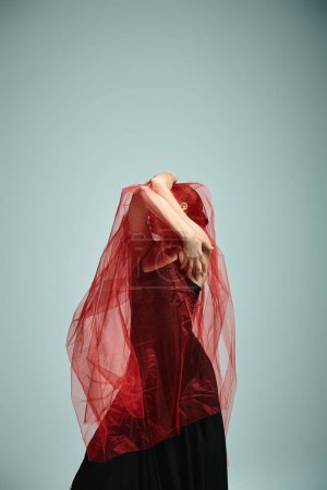 Foto de Joven, hermosa bailarina con un velo rojo bailando con gracia. - Imagen libre de derechos