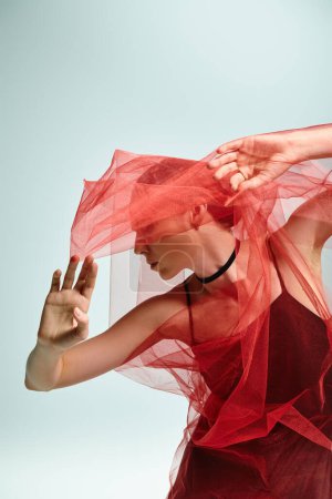 Foto de A young ballerina in a black dress gracefully moves with a veil over her head. - Imagen libre de derechos