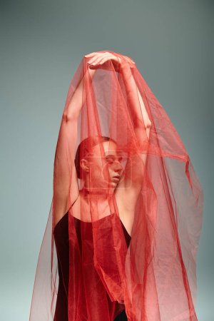Foto de Una joven bailarina baila con gracia con un vibrante velo rojo en la cabeza. - Imagen libre de derechos