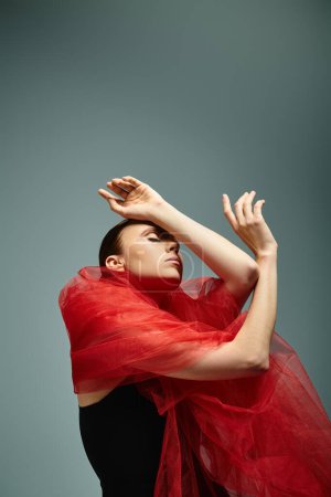 Young ballerina gracefully moves in a striking black dress and red shawl.
