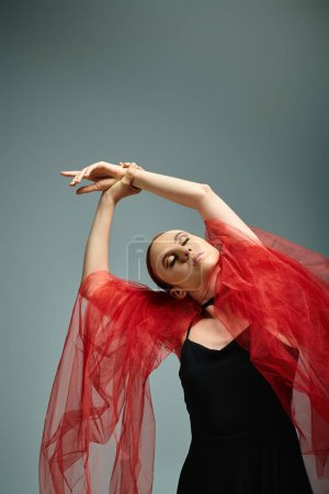 A young ballerina in a black dress and red veil dances gracefully.