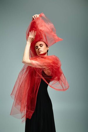 Téléchargez les photos : Une jeune, belle ballerine en robe noire et châle rouge, dansant gracieusement. - en image libre de droit