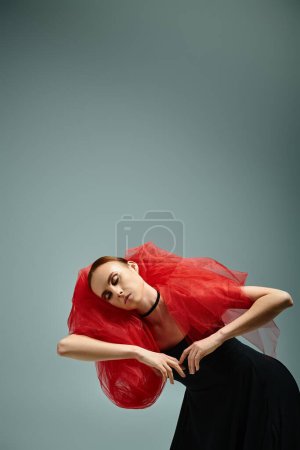 A young ballerina with red hair gracefully dances in a black dress.