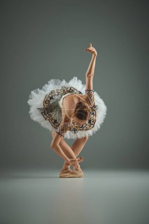 Eine junge schöne Ballerina in einem Tutu posiert anmutig, während sie en pointe tanzt.