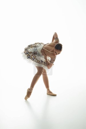 Young beautiful ballerina in a white dress dances gracefully.