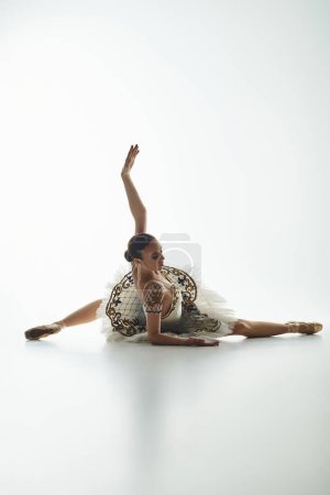 Jeune belle ballerine en robe blanche frappe une pose de danse dynamique.