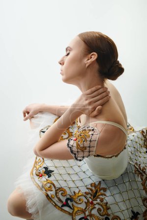 Une jeune femme en robe blanche et dorée tient gracieusement ses mains sur sa poitrine.