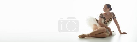 Téléchargez les photos : Une jeune ballerine est assise les jambes croisées sur le sol. - en image libre de droit