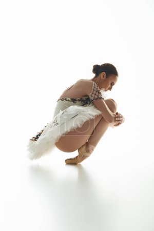 A young, beautiful ballerina in a costume gracefully kneels.