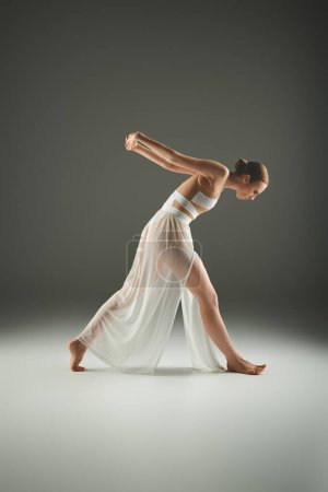 Téléchargez les photos : Une jeune, belle ballerine dans une robe blanche fluide danse gracieusement. - en image libre de droit