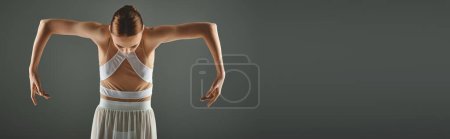 Foto de Elegante bailarina posa con confianza en un vestido blanco, las manos en las caderas. - Imagen libre de derechos