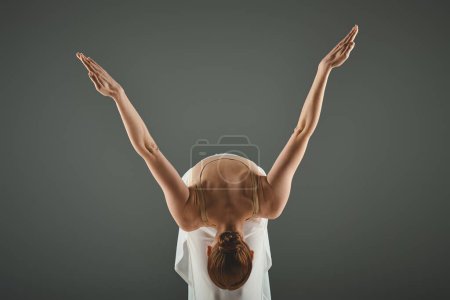 Téléchargez les photos : A young, beautiful ballerina with her hands raised elegantly in the air. - en image libre de droit