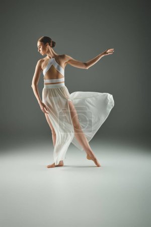 A young beautiful ballerina in a white dress dances gracefully.