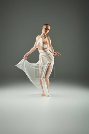 A young beautiful ballerina dances gracefully in a white dress.