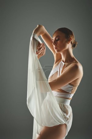 A young ballerina in a flowing white dress strikes a pose for the camera.