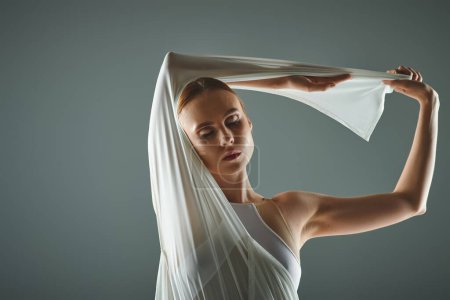 A young ballerina gracefully dances in a white dress with a veil.