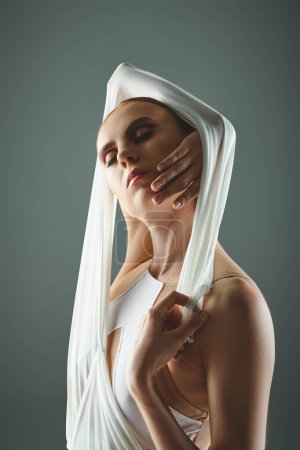A young, beautiful ballerina gracefully dances with a veil on her head.