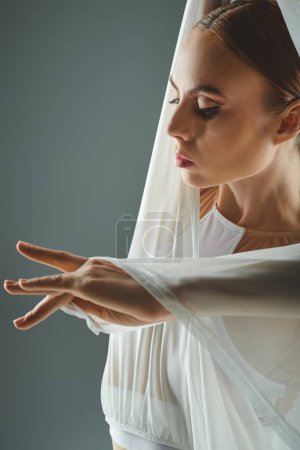 Una joven bailarina exhibe gracia y equilibrio en un vestido blanco, extendiendo sus manos con gracia.