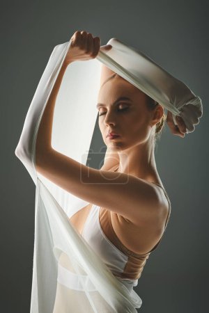 Jeune ballerine danse gracieusement, portant un voile sur la tête.