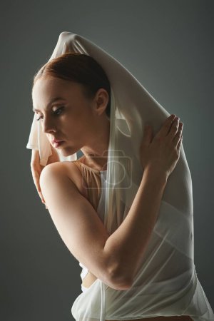 Talented young ballerina gracefully dances with a veil adorning her head.