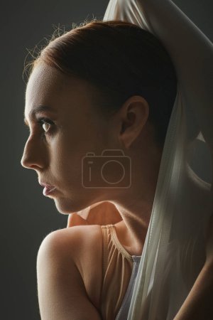 Photo for A young, beautiful ballerina gracefully dances with a veil draped over her head. - Royalty Free Image