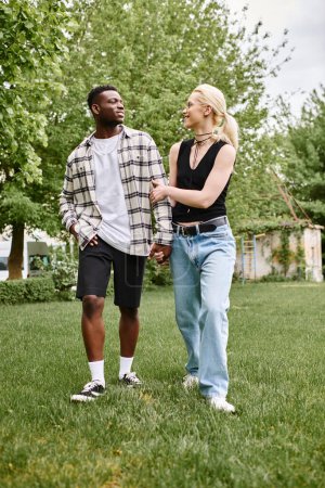 A multicultural couple, a happy African American man, and a Caucasian woman, standing together in lush green grass outdoors.