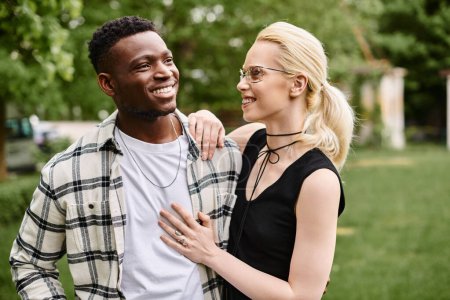 Ein multikulturelles Paar, ein afroamerikanischer Mann und eine kaukasische Frau stehen zusammen in einem Park und teilen einen Moment des Glücks.