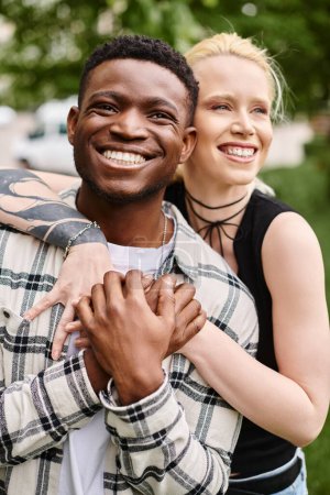Téléchargez les photos : Un couple multiculturel heureux un homme afro-américain tenant une femme blanche dans ses bras dans une étreinte romantique à l'extérieur dans un parc. - en image libre de droit