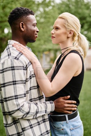 Ein glückliches multikulturelles Paar, ein afroamerikanischer Mann und eine kaukasische Frau, stehen zusammen im Freien in einem Park.