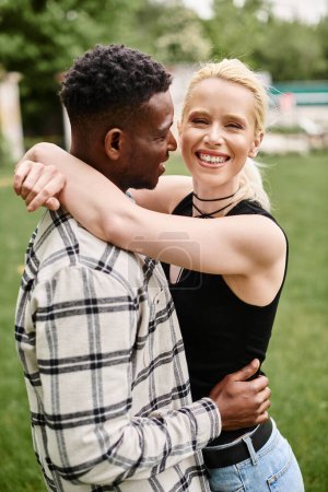 Una pareja feliz, formada por un hombre afroamericano y una mujer caucásica, abrazándose amorosamente en un vibrante entorno de parque.
