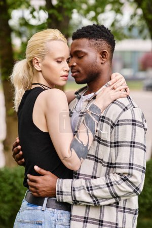 Ein glücklicher afroamerikanischer Mann und eine kaukasische Frau stehen nebeneinander und strahlen Freude in einer Parkanlage aus.