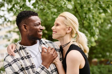 Un momento alegre capturado mientras una pareja multicultural comparte sonrisas genuinas en un parque.