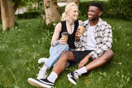Téléchargez les photos : Un couple multiculturel, un homme afro-américain et une femme caucasienne, s'assoient heureux ensemble sur l'herbe dans un parc. - en image libre de droit