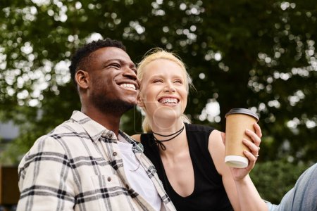 A happy multicultural couple, an African American man and a Caucasian woman, sitting together outdoors in a park.