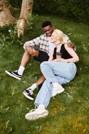 Photo for A content African American man and Caucasian woman sit together on lush green grass, enjoying a peaceful moment outdoors. - Royalty Free Image