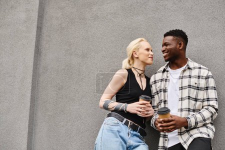 Una feliz pareja multicultural, un hombre y una mujer, de pie juntos en una calle urbana cerca de un edificio gris.