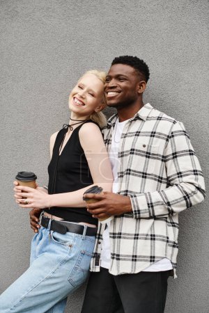 Téléchargez les photos : Un heureux couple multiculturel se tient côte à côte dans une rue urbaine près d'un bâtiment gris. - en image libre de droit