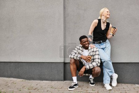 Téléchargez les photos : Un couple multiculturel s'assoit paisiblement les uns à côté des autres sur le trottoir urbain, partageant un moment tendre de convivialité. - en image libre de droit
