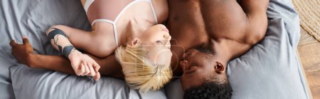 Una pareja multicultural acostada en una cama, exudando sensualidad y comodidad en cada uno abrazan.