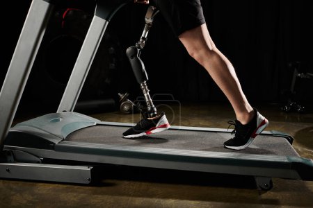 Téléchargez les photos : Une personne avec une jambe prothétique travaille sur un tapis roulant, avec une machine visible en arrière-plan. - en image libre de droit